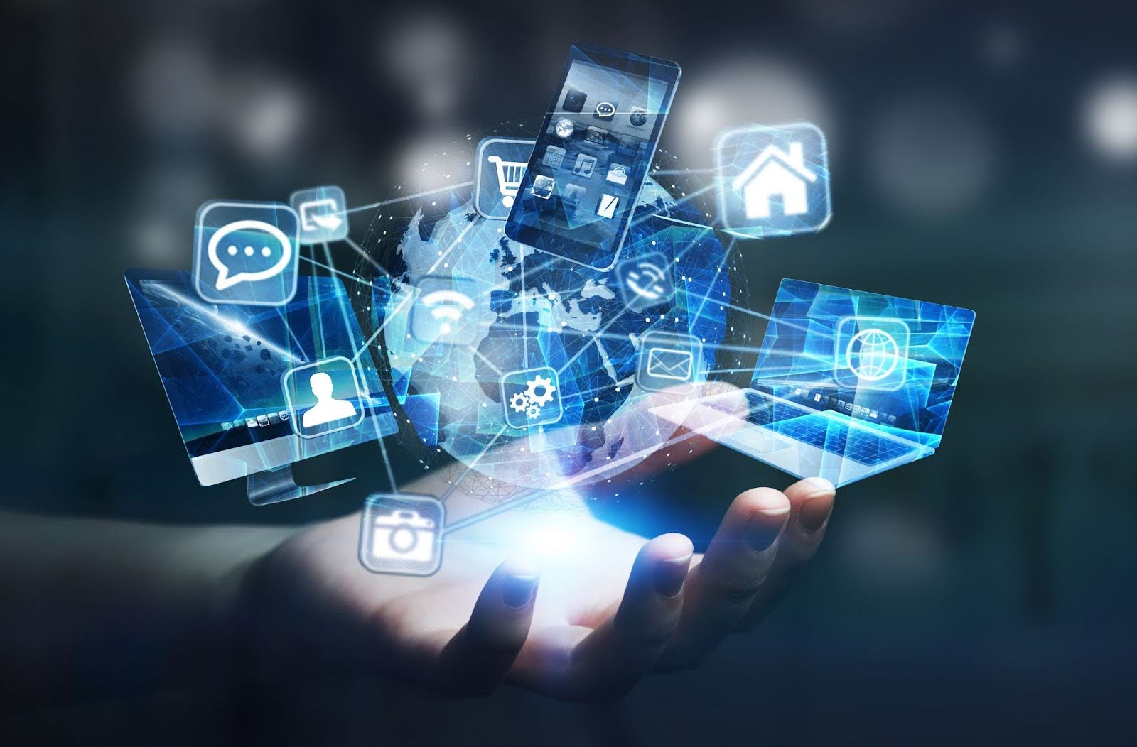 A person’s hand holding several phones, laptops, and tablets